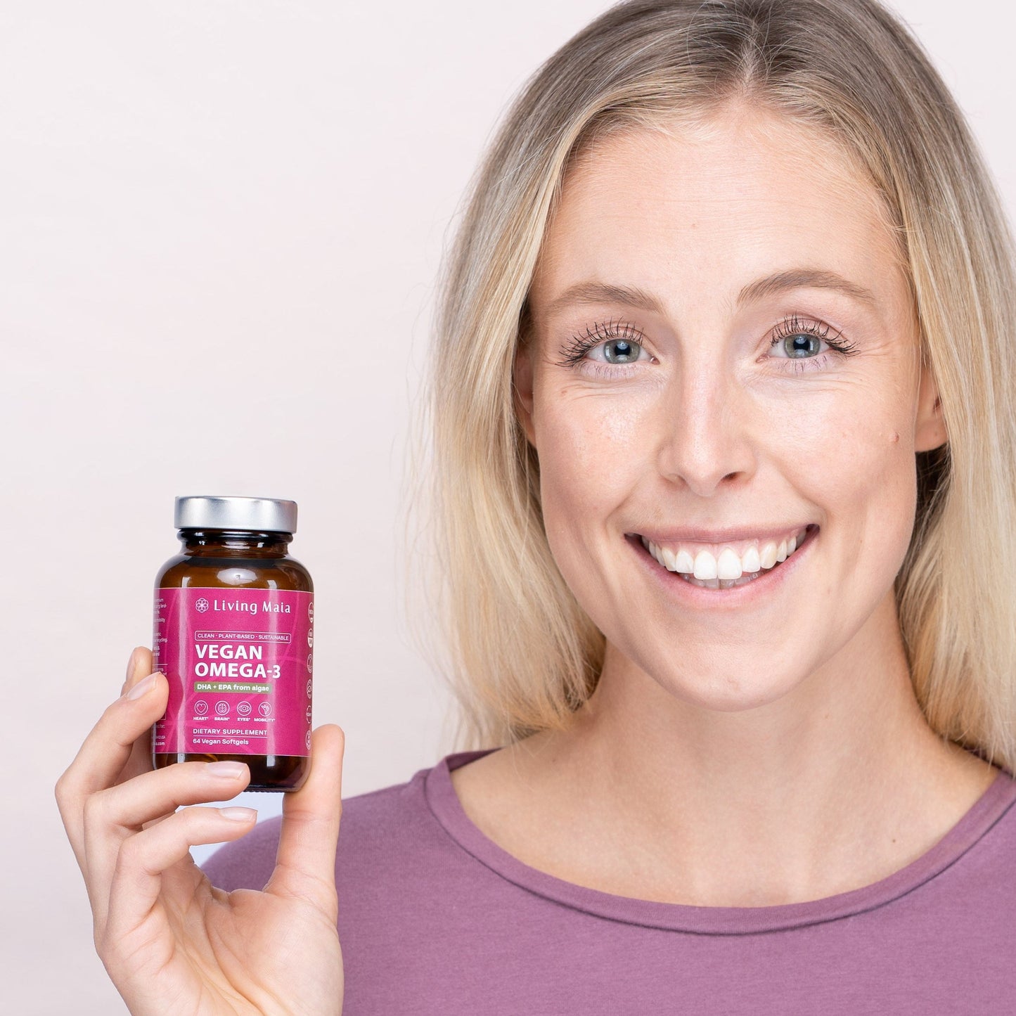 Woman holding a bottle of Living Maia vegan omega-3 with DHA and EPA derived from algae