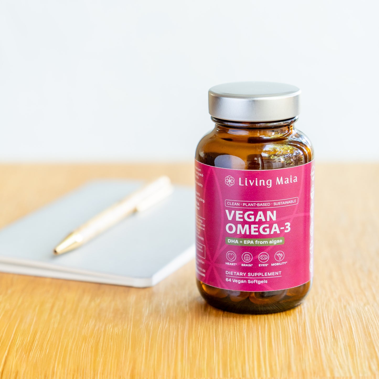 Living Maia vegan Omega-3 supplement bottle on desk with notebook and pen