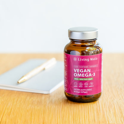 Living Maia vegan Omega-3 supplement bottle on desk with notebook and pen